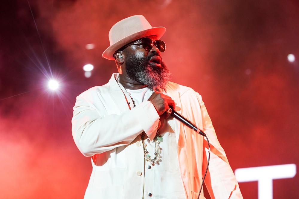 Black Thought holds a mic in an all white suite and white hat